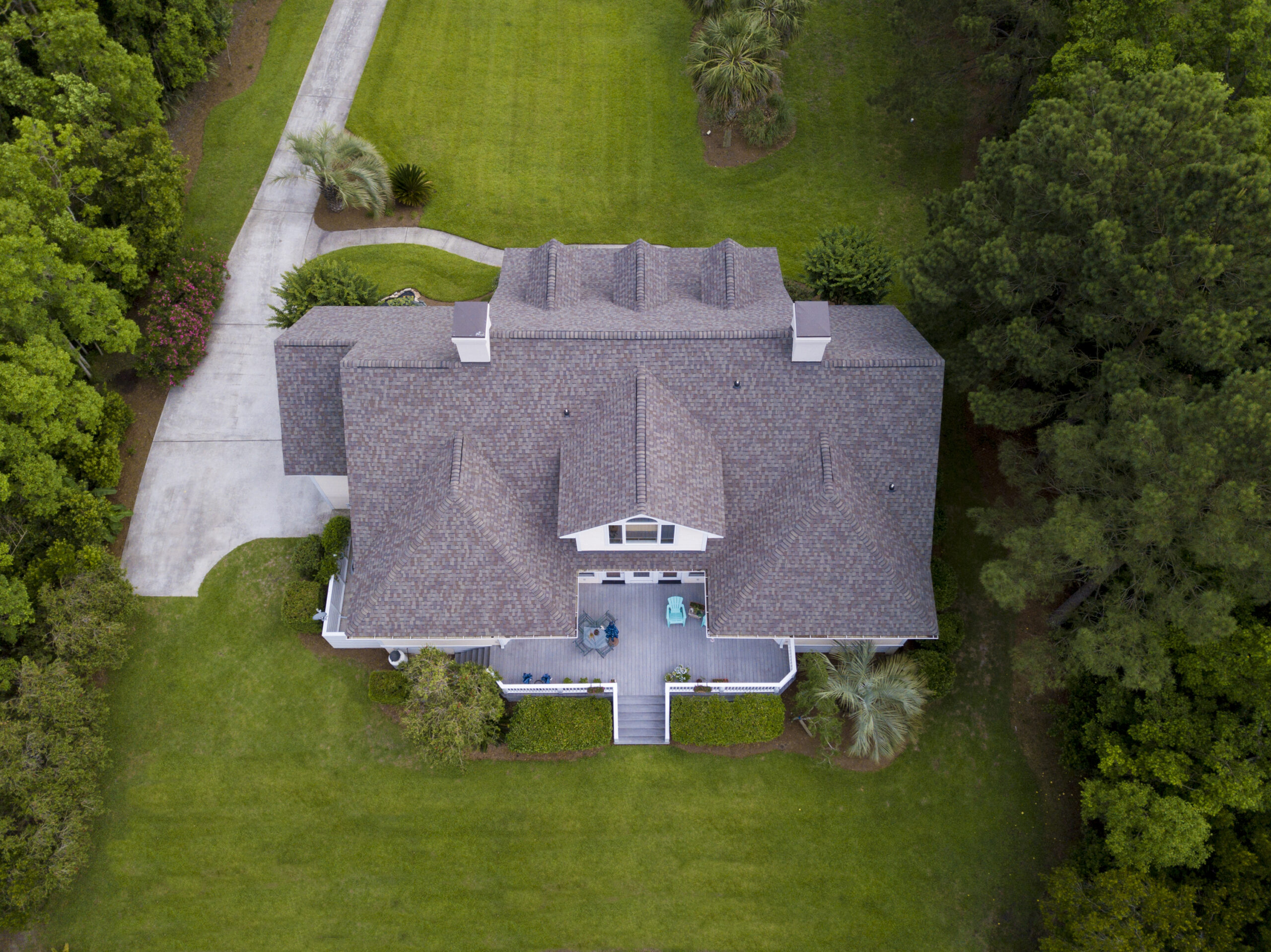 Aerial view of a large Central Texas home with a new roof under bright summer sun